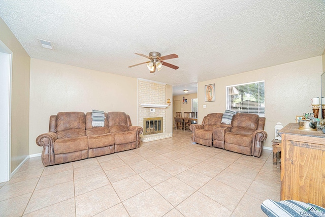 tiled living room with a textured ceiling, ceiling fan, and a fireplace