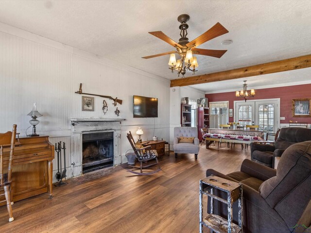 living room with ceiling fan with notable chandelier, wood-type flooring, and a textured ceiling