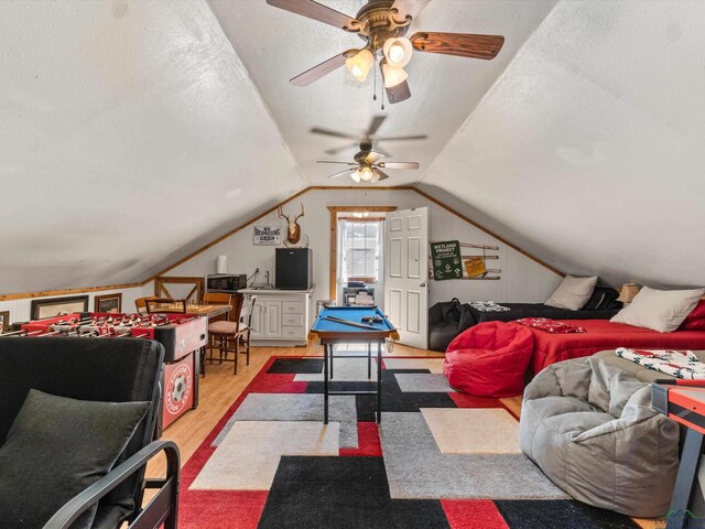 living room featuring ceiling fan, light hardwood / wood-style flooring, a textured ceiling, lofted ceiling, and pool table