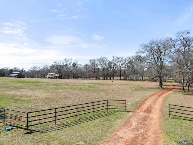 view of gate with a lawn and a rural view