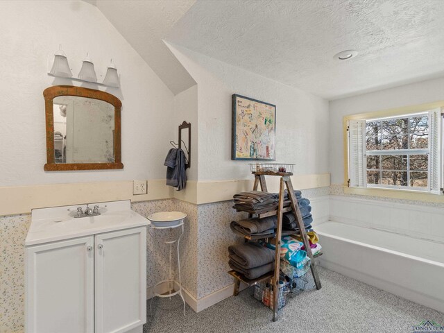 bathroom with a tub to relax in, vanity, and a textured ceiling