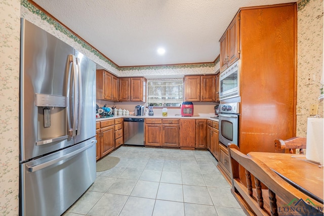 kitchen with light tile patterned flooring, stainless steel appliances, and a textured ceiling