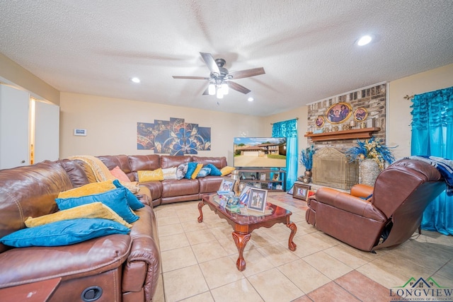 tiled living room with ceiling fan, a textured ceiling, and a brick fireplace