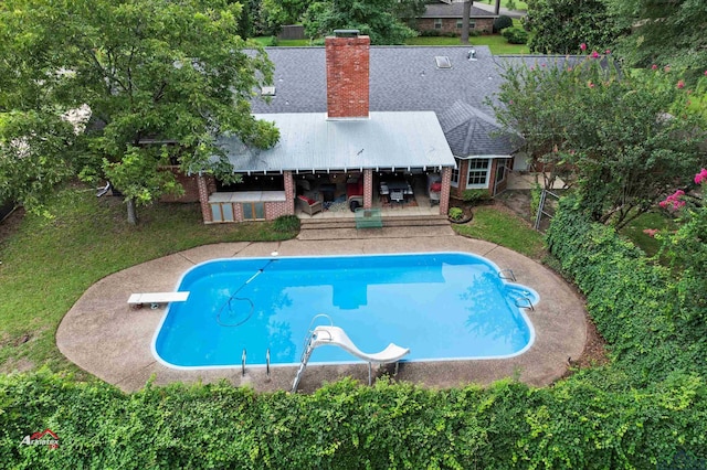 view of swimming pool featuring a patio area, a diving board, and a water slide