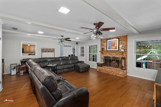 living room featuring ceiling fan, dark hardwood / wood-style floors, ornamental molding, a fireplace, and beam ceiling