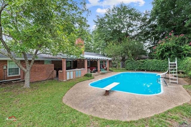 view of swimming pool with a patio, a diving board, a lawn, and a water slide