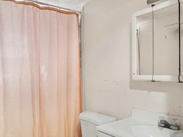 bathroom with vanity, toilet, and a textured ceiling