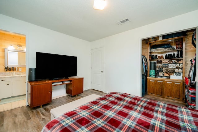 bedroom with a textured ceiling, light hardwood / wood-style flooring, and ensuite bath