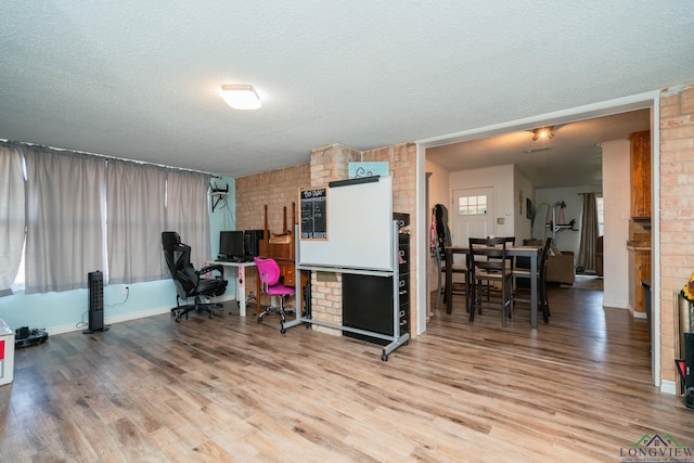 office space with hardwood / wood-style flooring, a textured ceiling, and brick wall