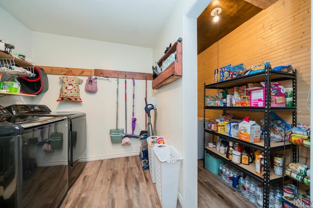 laundry area featuring wooden walls, hardwood / wood-style floors, and independent washer and dryer