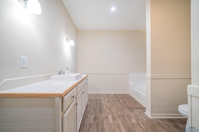 bathroom featuring hardwood / wood-style flooring, vanity, toilet, and a washtub