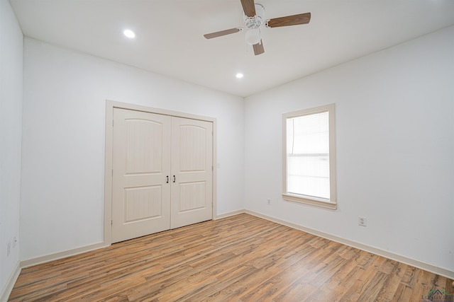 unfurnished bedroom featuring ceiling fan, light hardwood / wood-style floors, and a closet