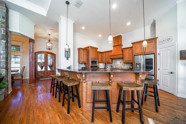 kitchen with french doors, a breakfast bar area, appliances with stainless steel finishes, pendant lighting, and decorative backsplash