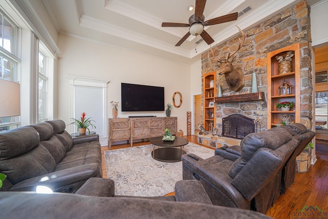 living room featuring a fireplace, hardwood / wood-style flooring, ceiling fan, a raised ceiling, and crown molding