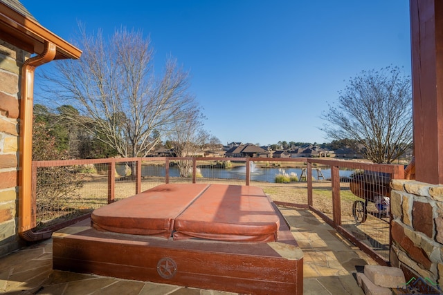 view of patio / terrace featuring a covered hot tub and a water view