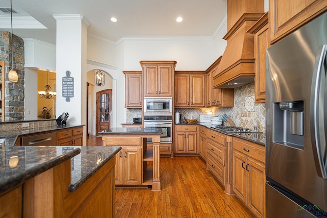 kitchen featuring pendant lighting, tasteful backsplash, ornamental molding, stainless steel appliances, and custom range hood