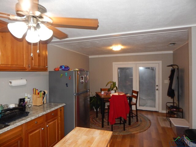 224 Hilltop Ave, Gilmer, TX 75644 - kitchen with freestanding refrigerator, brown cabinetry, wood finished floors, a ceiling fan, and light stone counters