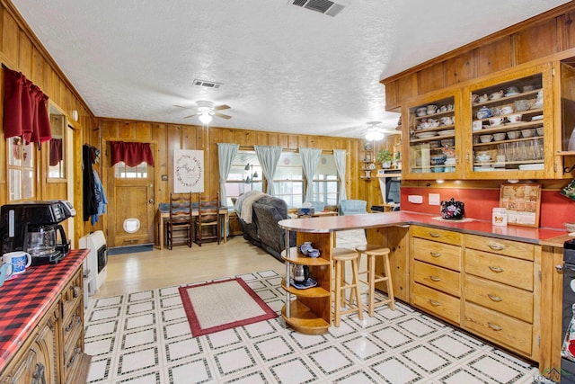 kitchen featuring a textured ceiling, wooden walls, kitchen peninsula, and ceiling fan