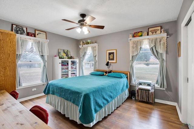 bedroom with ceiling fan, wood-type flooring, multiple windows, and a textured ceiling