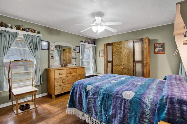 bedroom with a textured ceiling, wood-type flooring, and ceiling fan