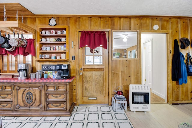 interior space featuring light wood-type flooring, heating unit, a textured ceiling, and wooden walls