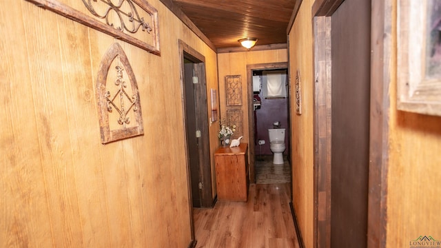 hall with wooden walls, wood ceiling, and light hardwood / wood-style floors