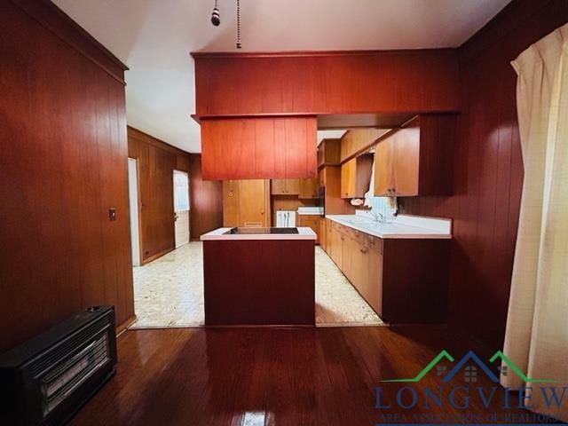 kitchen featuring cooktop, dark hardwood / wood-style floors, heating unit, and wood walls