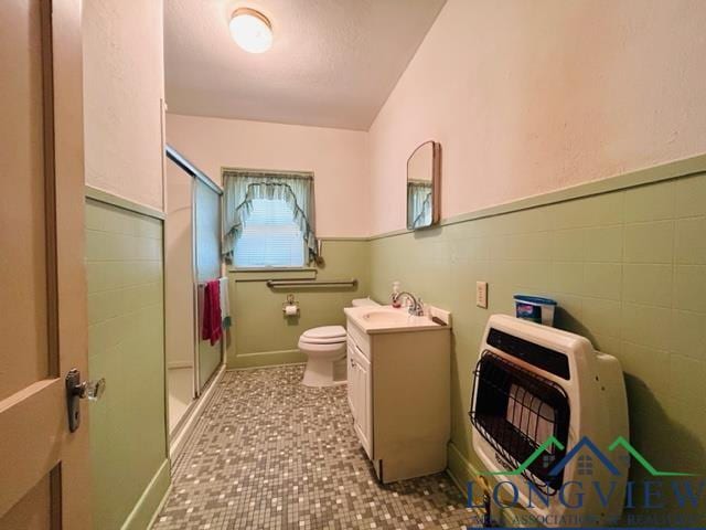 bathroom with vanity, heating unit, toilet, and walk in shower