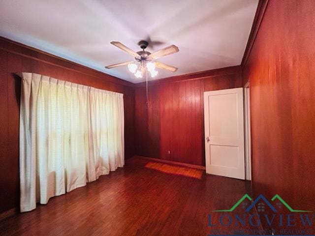 unfurnished room featuring ceiling fan, wooden walls, and wood finished floors