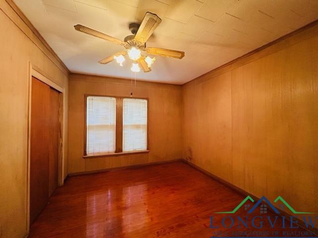 unfurnished room with ceiling fan, crown molding, and dark wood-type flooring