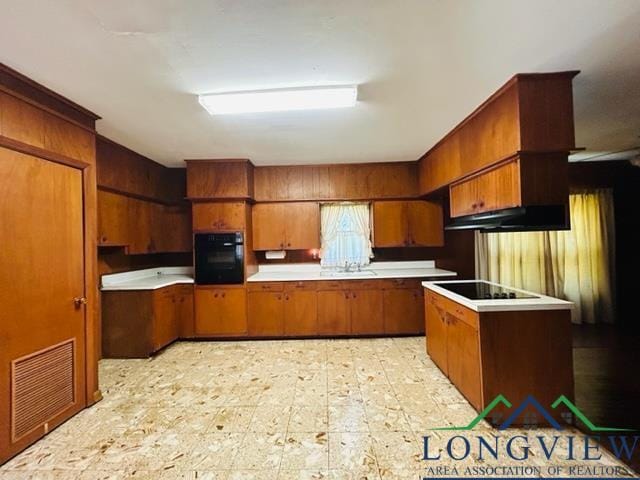 kitchen with brown cabinets, light floors, light countertops, visible vents, and black appliances