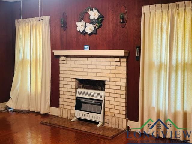 living area with a fireplace, heating unit, and wood finished floors