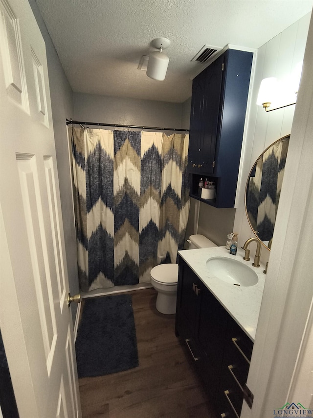 1101 N Idlewood Dr, White Oak, TX 75693 - full bathroom featuring wood finished floors, vanity, toilet, a shower with shower curtain, and a textured ceiling
