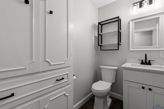 813 Kenwood Ln, Longview, TX 75604 - half bathroom featuring wood finished floors, baseboards, toilet, and vanity