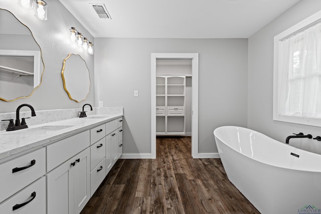 813 Kenwood Ln, Longview, TX 75604 - full bath with wood finished floors, a walk in closet, a freestanding bath, double vanity, and baseboards