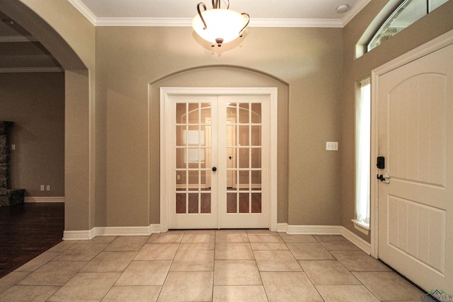 tiled entrance foyer with crown molding, a wealth of natural light, and french doors