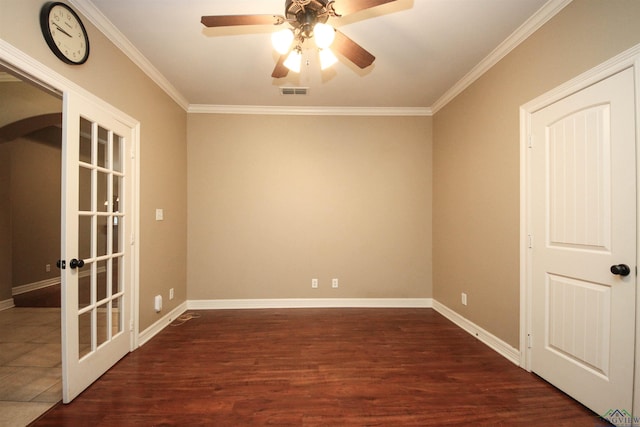 empty room with ceiling fan, dark hardwood / wood-style floors, ornamental molding, and french doors