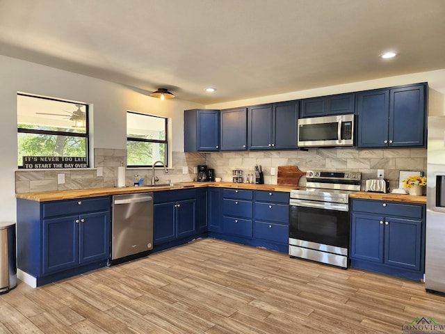 kitchen featuring blue cabinetry, appliances with stainless steel finishes, light wood-type flooring, and butcher block counters