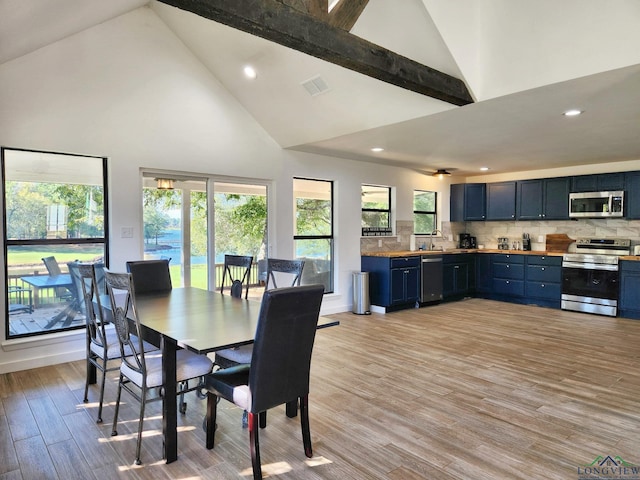dining area with beamed ceiling, light wood-type flooring, and high vaulted ceiling
