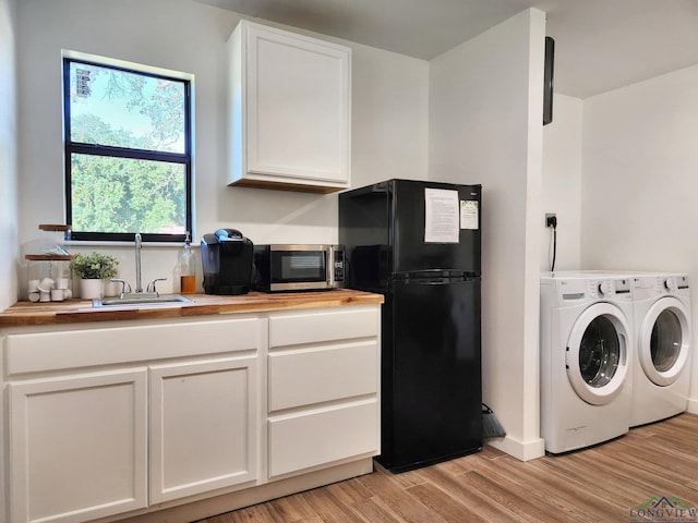 kitchen featuring black fridge, light hardwood / wood-style flooring, wooden counters, independent washer and dryer, and white cabinets