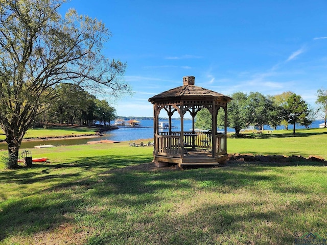 view of property's community with a gazebo, a water view, and a lawn