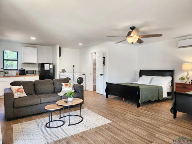bedroom with ceiling fan, light hardwood / wood-style floors, a wall mounted air conditioner, and independent washer and dryer