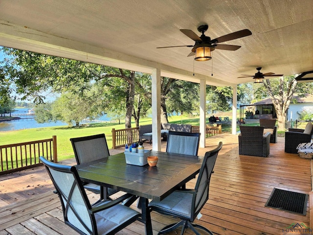 wooden deck featuring a water view, ceiling fan, and a lawn