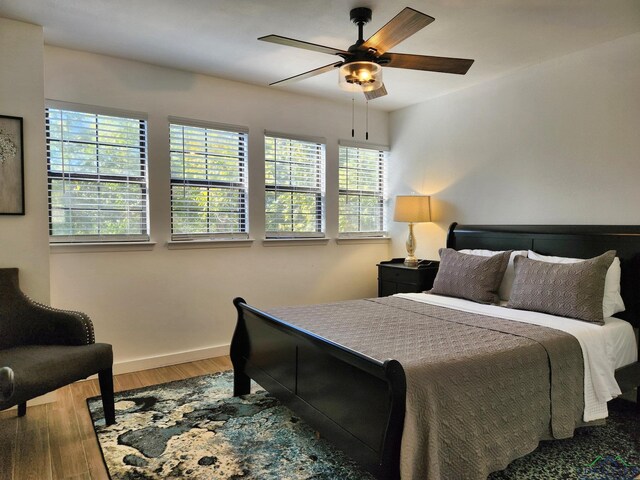 bedroom featuring multiple windows, ceiling fan, and hardwood / wood-style flooring