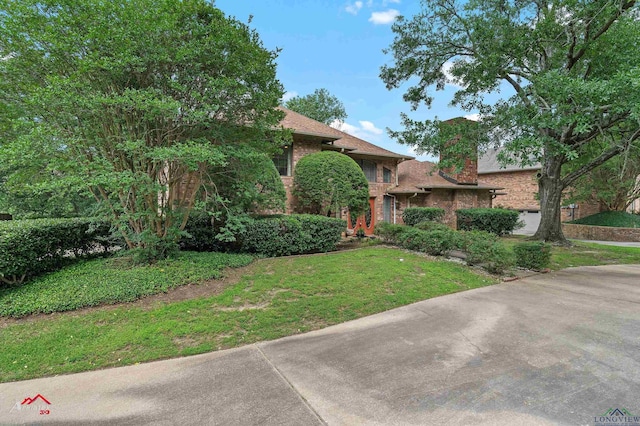 1502 Meandering Way, Longview, TX 75604 - view of property hidden behind natural elements with brick siding, a front lawn, and a chimney