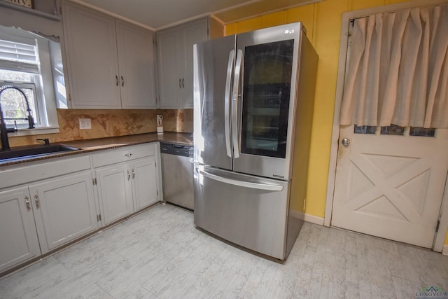 kitchen featuring tasteful backsplash, appliances with stainless steel finishes, gray cabinets, and sink