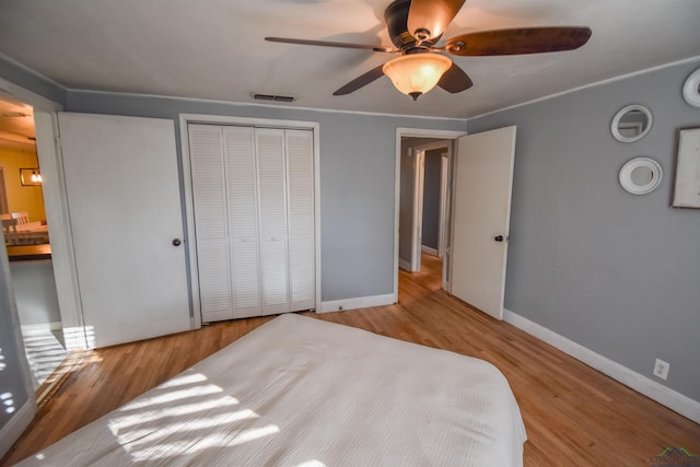 bedroom with light wood-type flooring, ceiling fan, and a closet