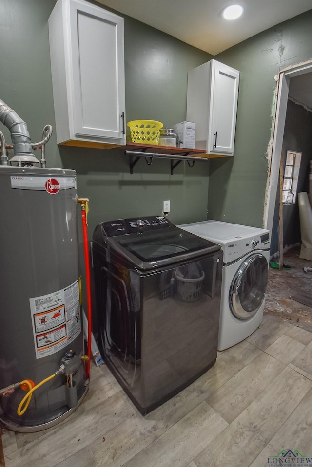 laundry area featuring cabinets, gas water heater, washer and dryer, and light wood-type flooring