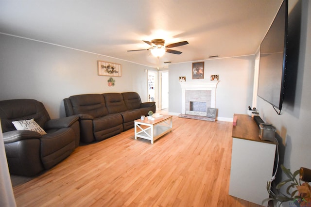 living room with wood-type flooring, a brick fireplace, and ceiling fan