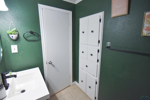 bathroom featuring tile patterned flooring, crown molding, and sink